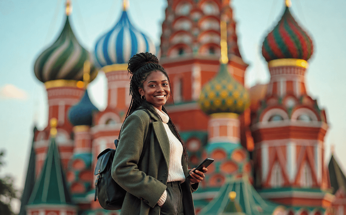 Smiling student holding a notebook in front of St Basil's Cathedral in Moscow