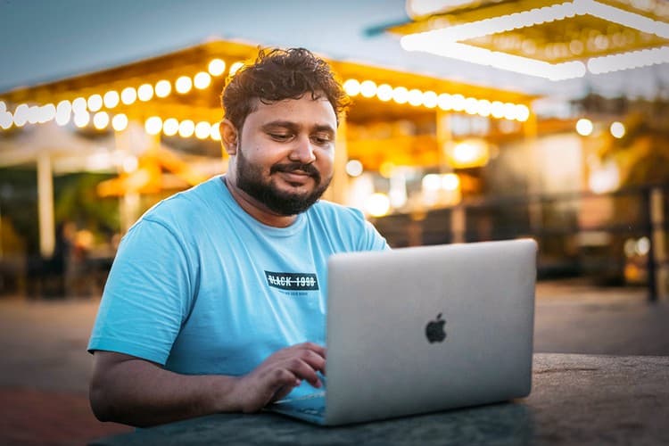Student learning Russian online on a laptop at an outdoor café in the evening